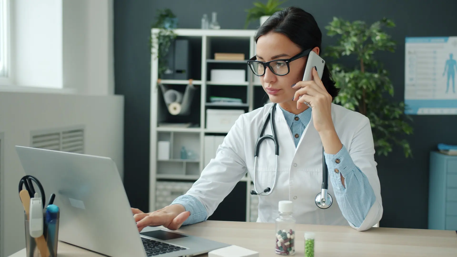 Doctora atendiendo en su consultorio con el expediente del paciente en la computadora